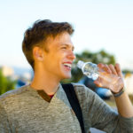 Homme sportif buvant de l'eau minerale à la bouteille