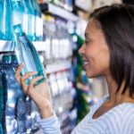 Une femme choisit une bouteille d'eau en magasin